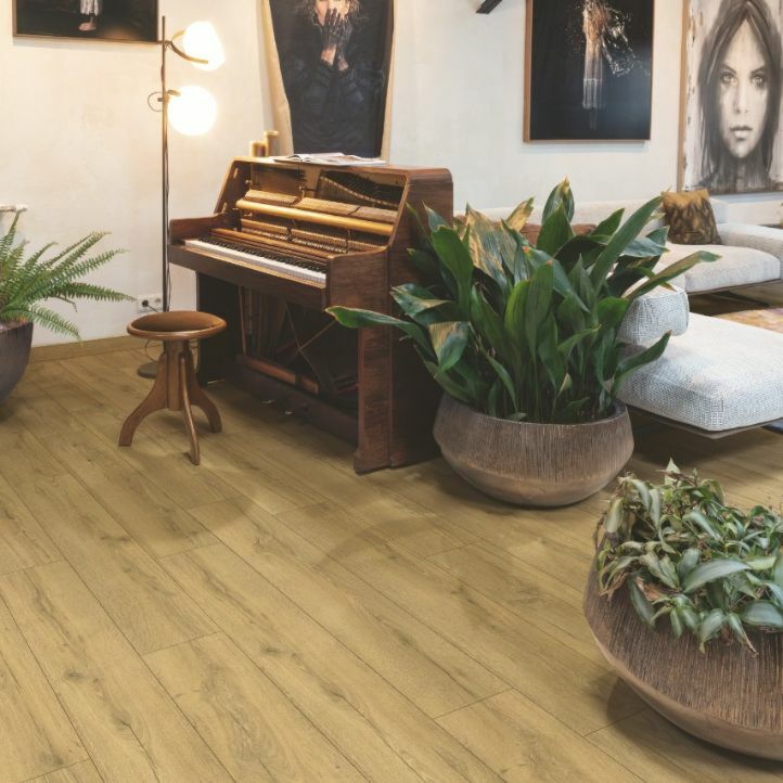 Suelo laminado de la marca Quick-step de la serie CLASSIC Roble crudo arena instalado en un salon con sillas