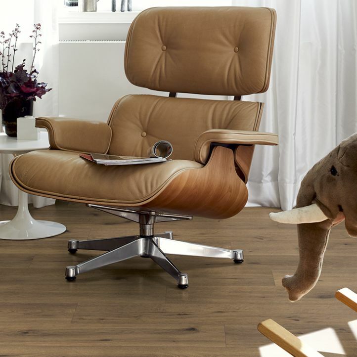 Suelo laminado Roble Inuvik EHL148 marca Egger Home instalado en un salón con una silla marrón