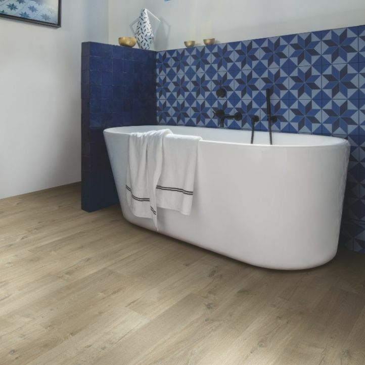suelo laminado quick-step roble suave marrón claro de la gama impressive instalado en el baño con una bañera