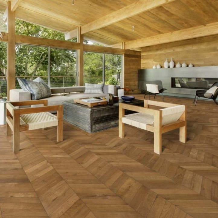 suelo de madera natural multicapa con un diseño chevron de kahrs roble suave marrón instalado en un salón en una cabaña rústica