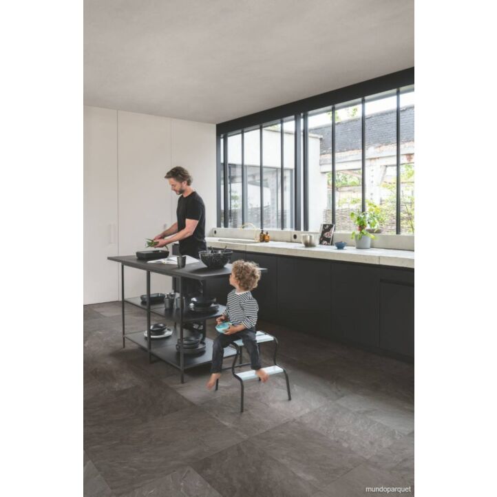 Suelo laminado de Quick-Step de la colección Muse pizarra gris instalado en una cocina con un hombre cocinando y un niño mirando