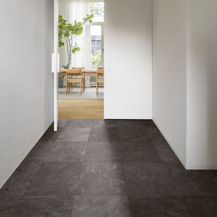 Suelo laminado de Quick-Step de la colección Muse pizarra gris instalado en una cocina con un hombre cocinando y un niño mirando