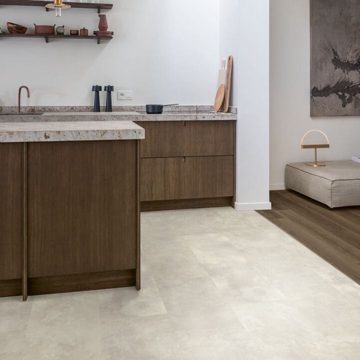 Suelo laminado de Quick-Step de la colección Muse Hormigón Moteado instalado en un ambiente de salón con un hombre leyendo y un perro visto de más cerca
