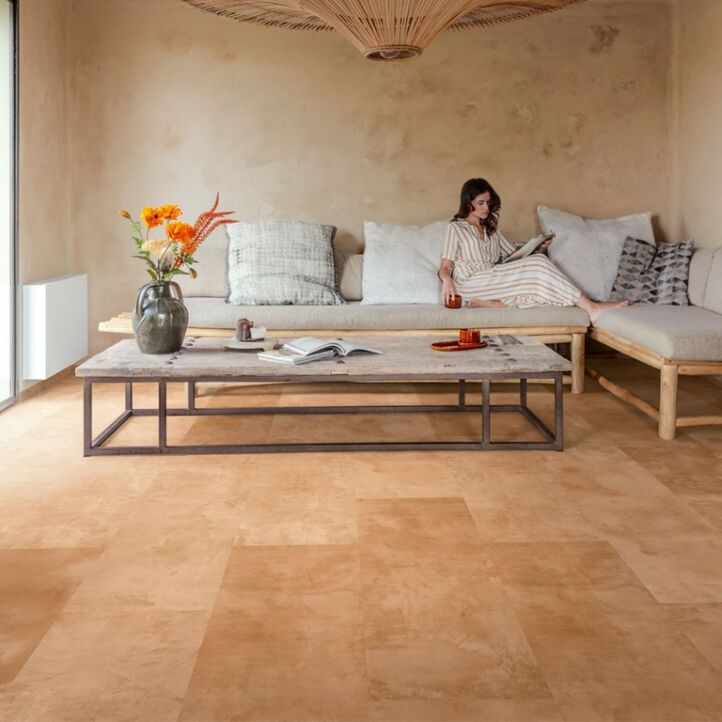 Suelo laminado de Quick-Step de la colección Muse Terracota instalado en una sala de estar con una mujer leyendo