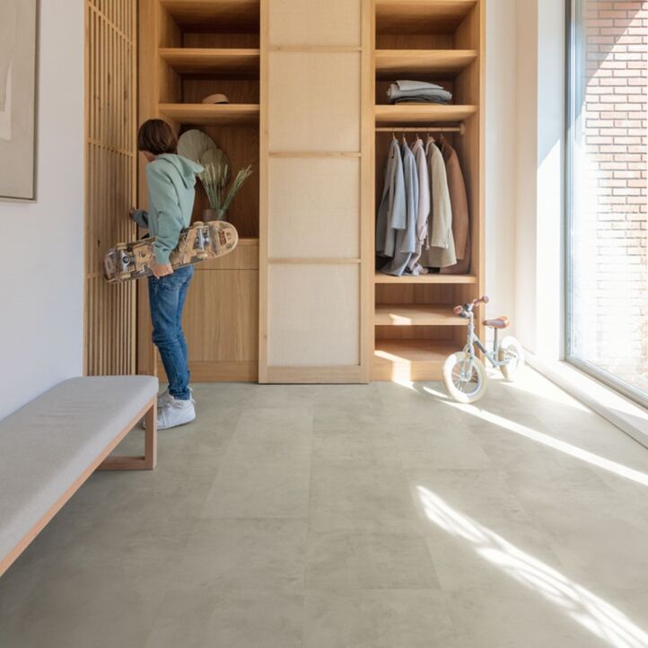Suelo laminado de Quick-Step de la colección Muse hormigón gris instalado en una cocina con una mujer lavando los platos.