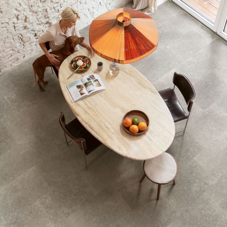Suelo laminado de Quick-Step de la colección Muse Arenisca Azul Oscuro instalado en un ambiente de salón con un perro bebiendo agua
