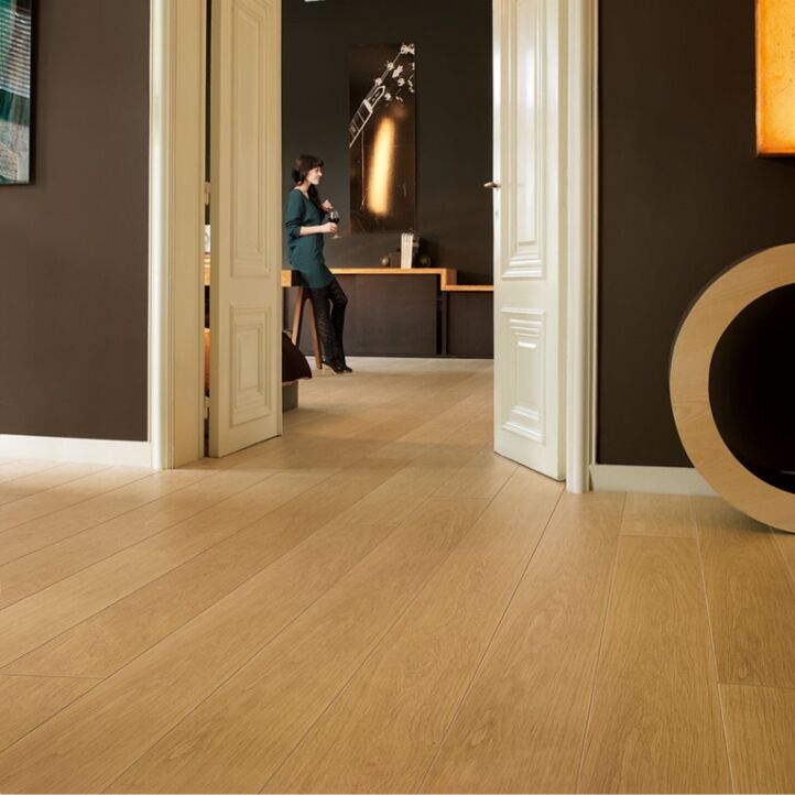 Parquet laminado de roble barnizado natural de la marca quick-step de la serie largo en un ambiente de habitación.