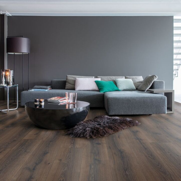 Parquet laminado de roble desierto marrón oscuro cepillado de la marca quick-step de la serie majestic en un ambiente de habitación.