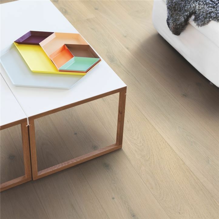 suelo multicapa de madera de la marca pergo roble aurora boreal en un ambiente detalle con una mesa y sofá