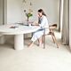 Suelo laminado de Quick-Step de la colección Muse Tiza instalado en un salón con una mujer sentada en una silla leyendo