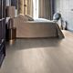 Parquet laminado de roble desierto marrón oscuro cepillado de la marca quick-step de la serie majestic en un ambiente de habitación.