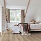 Parquet laminado de roble desierto gris cepillado de la marca quick-step de la serie majestic en un ambiente de habitación.
