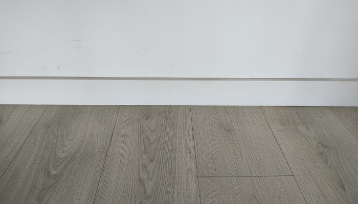 rodapie lacado blanco instalado con suelo laminado gris